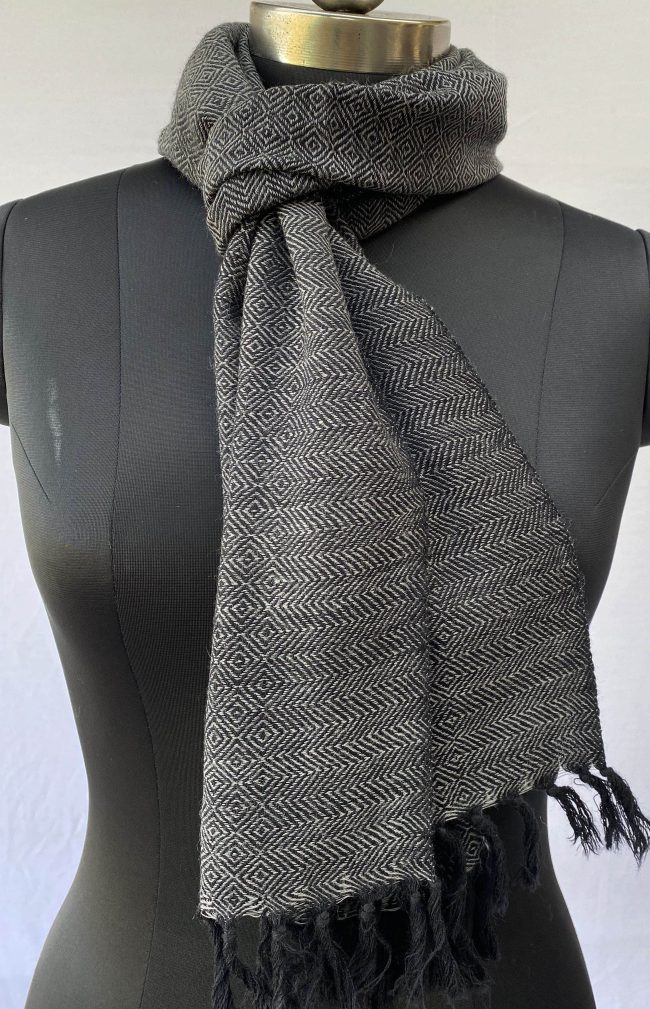 Pure merino wool scarf in black with white undertones. With diamond and herringbone patterns in its weave