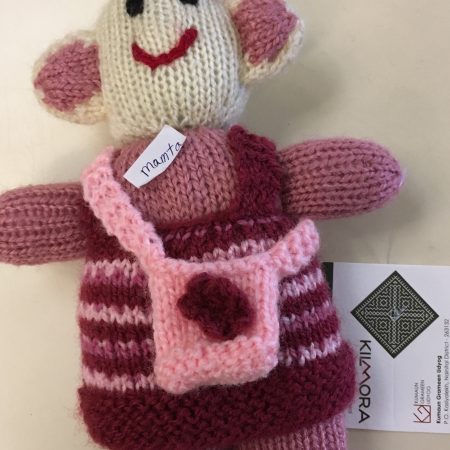 Knitted soft toy of a little girl with small bag slung crossways