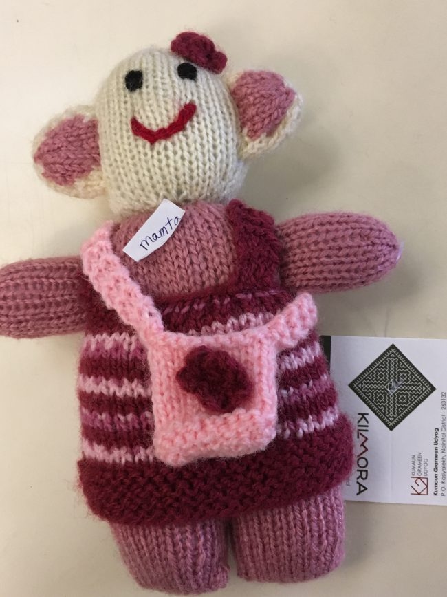 Knitted soft toy of a little girl with small bag slung crossways