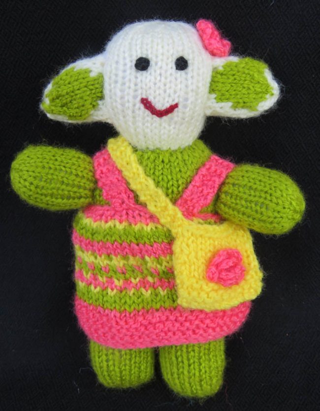 Knitted soft toy of a little girl with small bag slung crossways