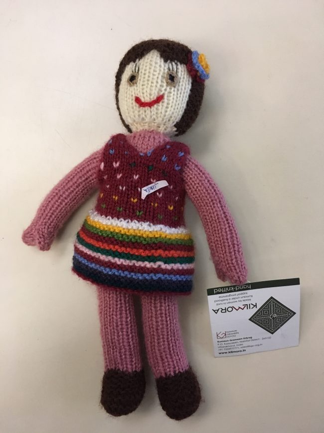 Knitted soft toy of a small girl wearing a polka dotted frock