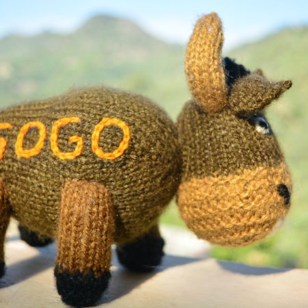 Knitted toy of a bison in brown with name Gogo kntted on the side