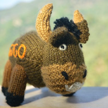 Knitted toy of a bison in brown with name Gogo kntted on the side