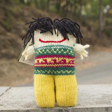 Knitted soft toys of funky looking person with wild black hair and a mischevious smile