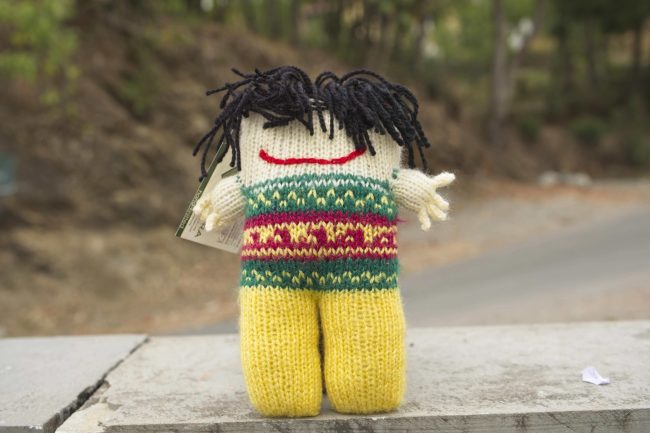 Knitted soft toys of funky looking person with wild black hair and a mischevious smile