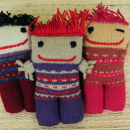 Knitted soft toys of funky looking little people with wild orange or black hair and a mischevious smile