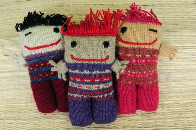 Knitted soft toys of funky looking little people with wild orange or black hair and a mischevious smile