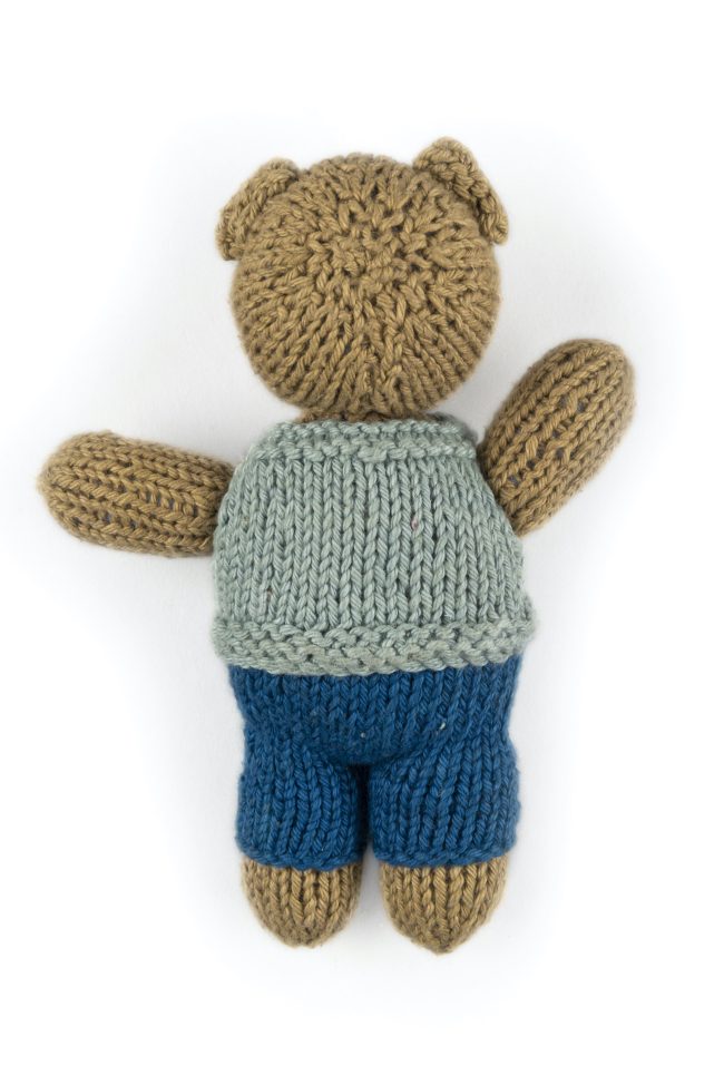 Hand-knit toy bear with dark blue trouser, light blue vest with red buttons