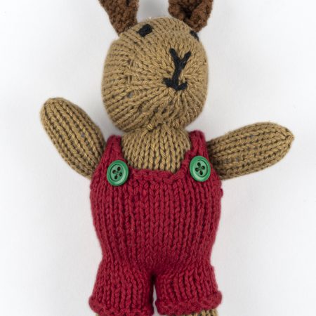 Hand-knit cotton toy of a rabbit wearing a red jumper with green buttons