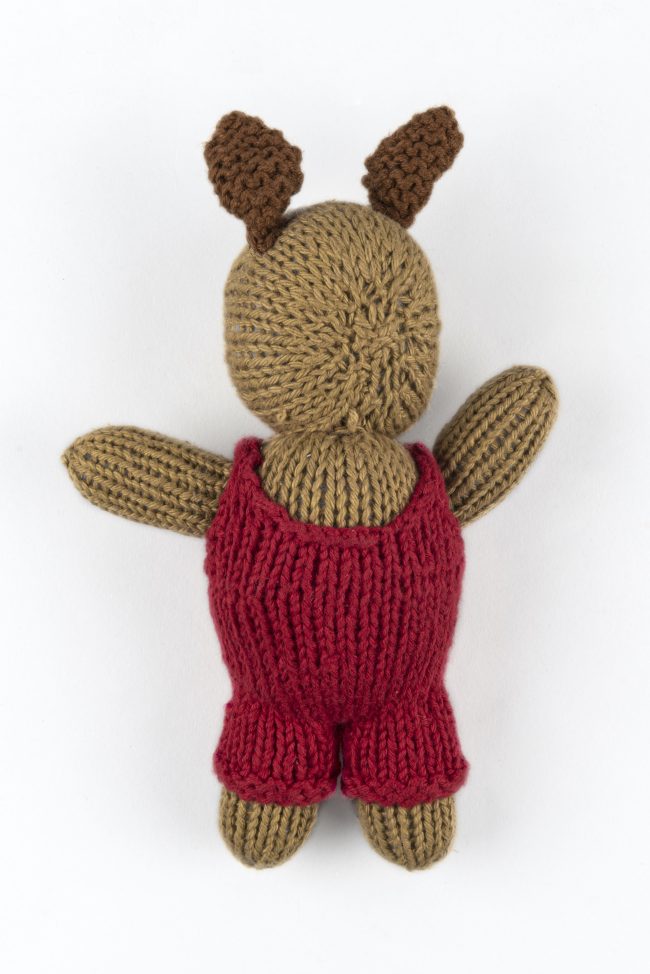 Hand-knit cotton toy of a rabbit wearing a red jumper with green buttons