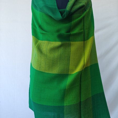 Bold checked merino wool shawl draped on a mannequin. In shades of lime green, sage green, leaf green, and deep emerald green