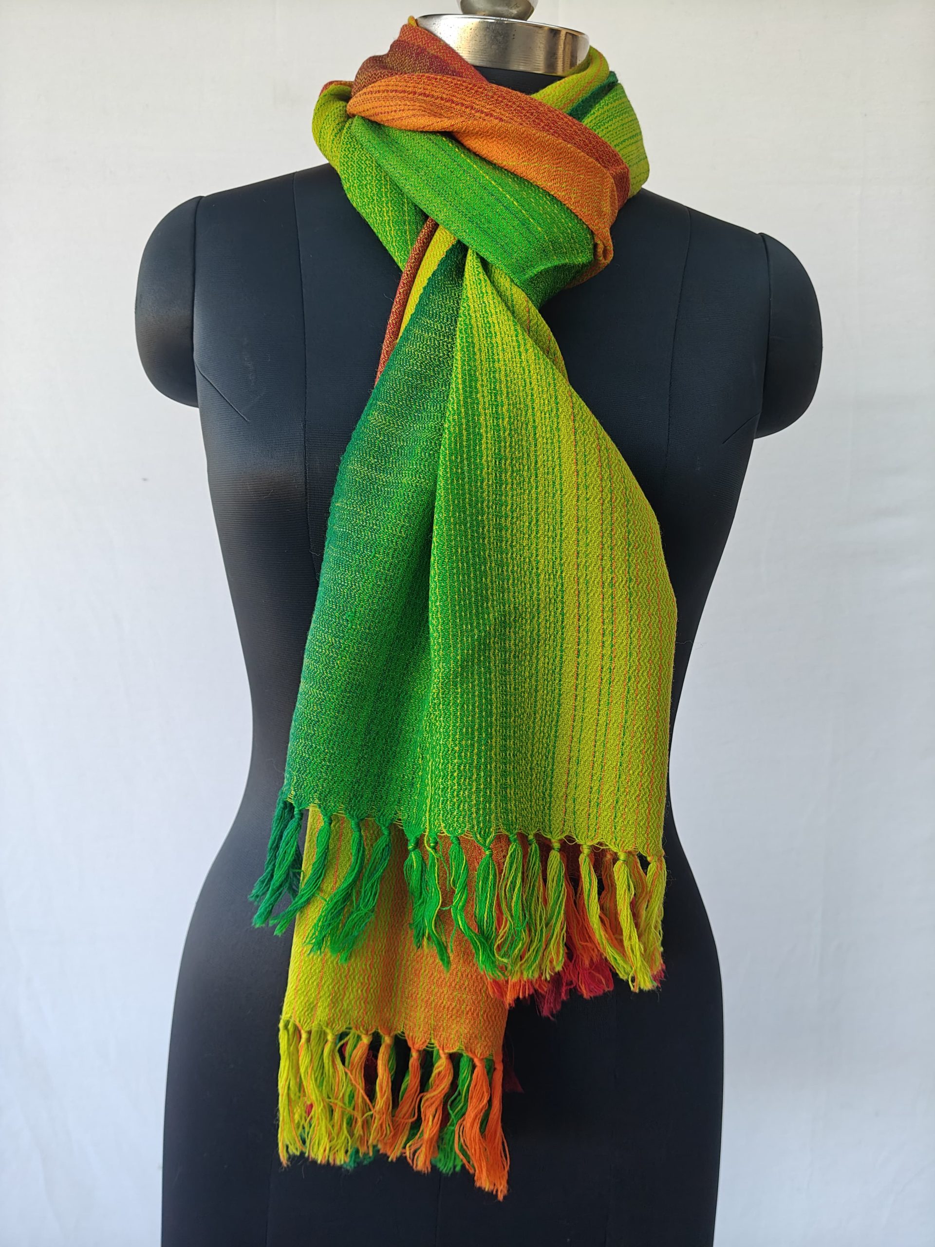 Merino wool stole knotted on a mannequin. In gradation weave - in shades of forest, shamrock and lime green followed by autumnal orange and mahogany